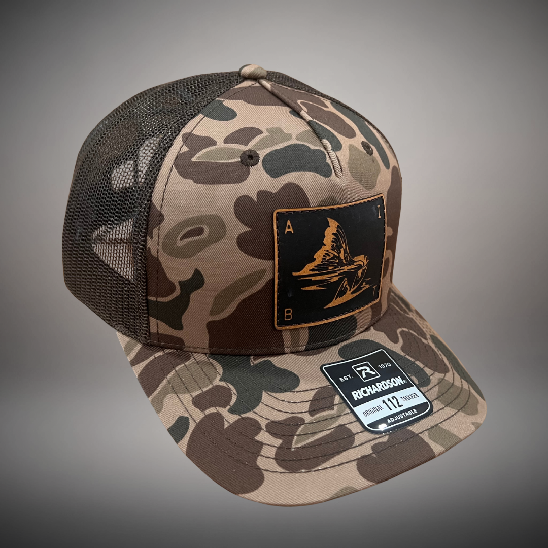 AIBT redfish tail leather patch trucker hat Richardson 112 in duck camo bark - studio view