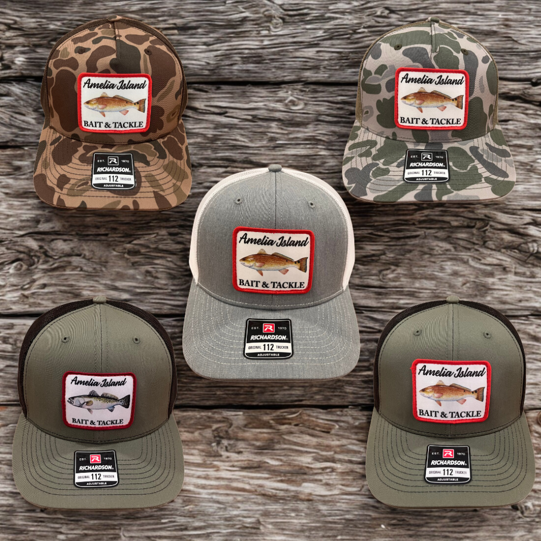 Five baseball caps with 'Amelia Island Bait & Tackle' logo on a wooden surface